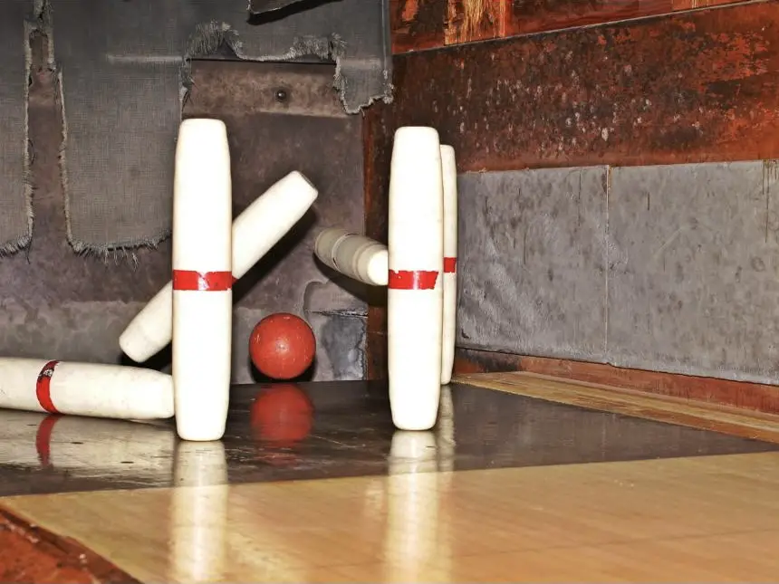 Candlepin bowling pins knocked down by a red ball